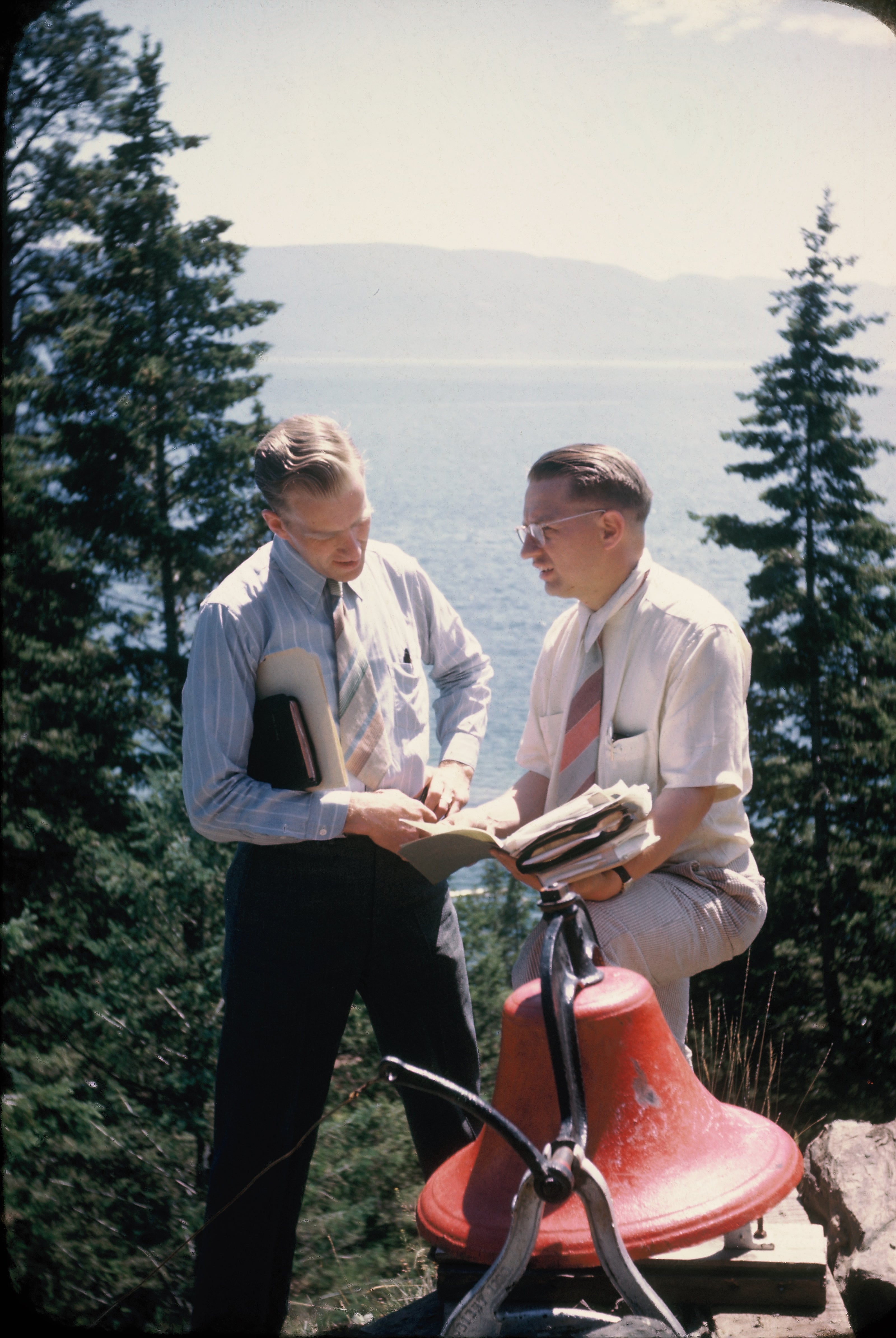 In 1946 Mr. Stima and Rev. Loddings visit on Bell Point, which was the site of the future indoor chapel and retreat center, now called Hagen Hall.  Today this red bell is in the Hagen Hall bell tower. It still wakes campers in the morning  and calls people to worship and meals. 